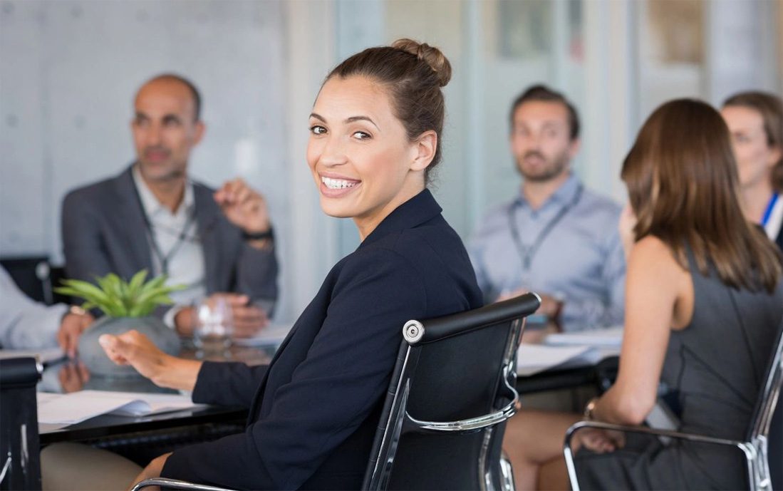 A woman sitting in front of other people at a table.